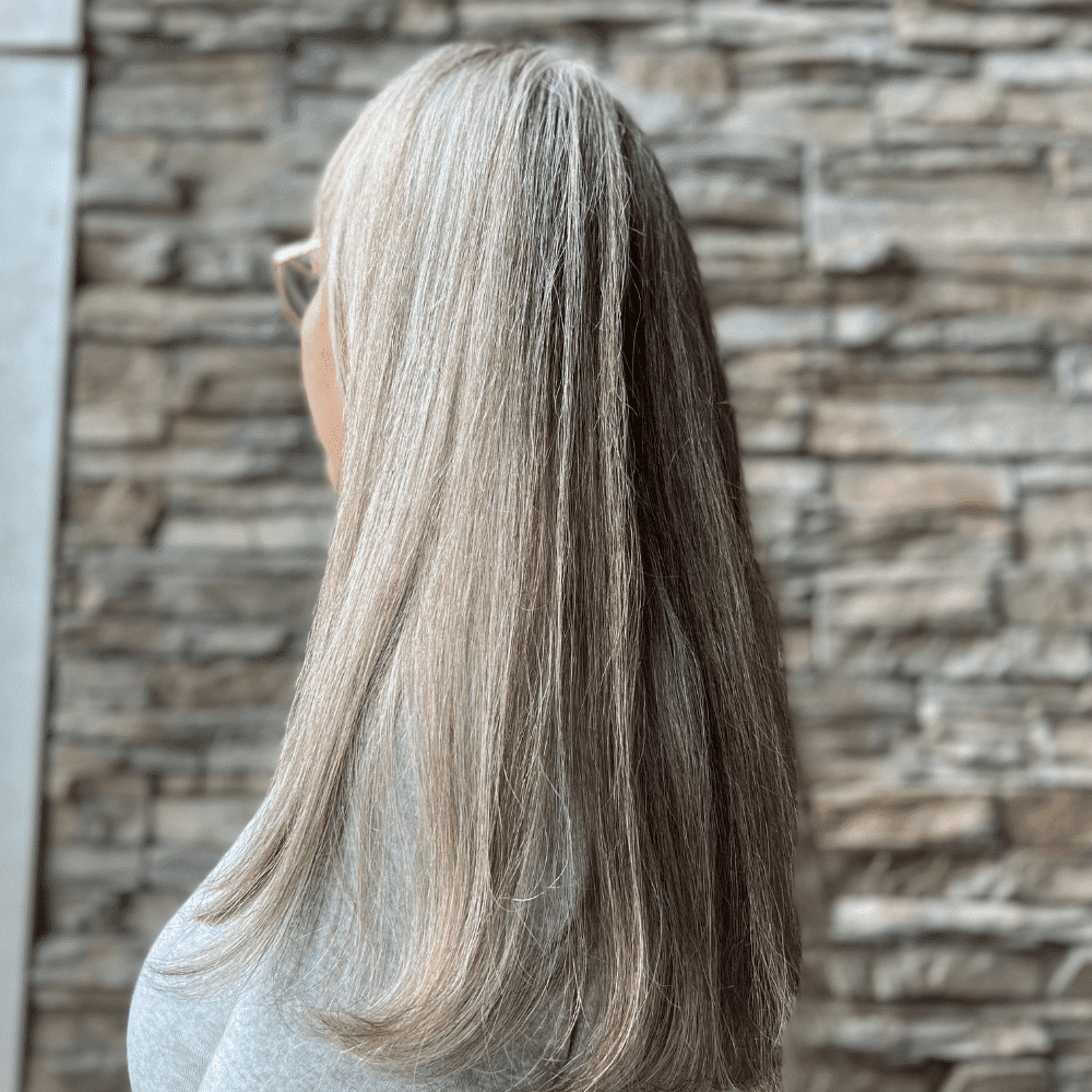 Long silver hair against a stone wall background, viewed from the side.